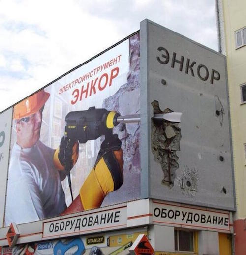 outdoor ad on 2 faces of building shows drill sticking out of one wall