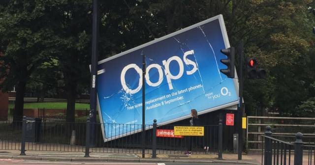Billboard that looks like it's fallen, shattering its glass. Ad reads "OOPS"